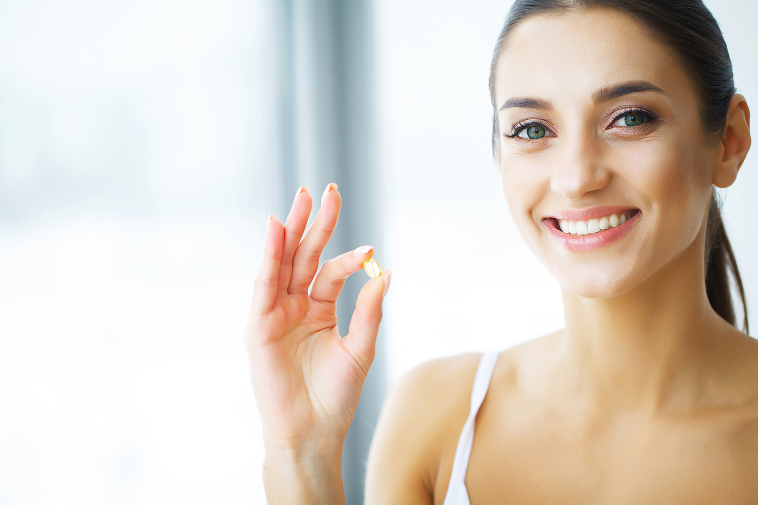 Woman with glowing healthy skin about to take her fish oil supplement