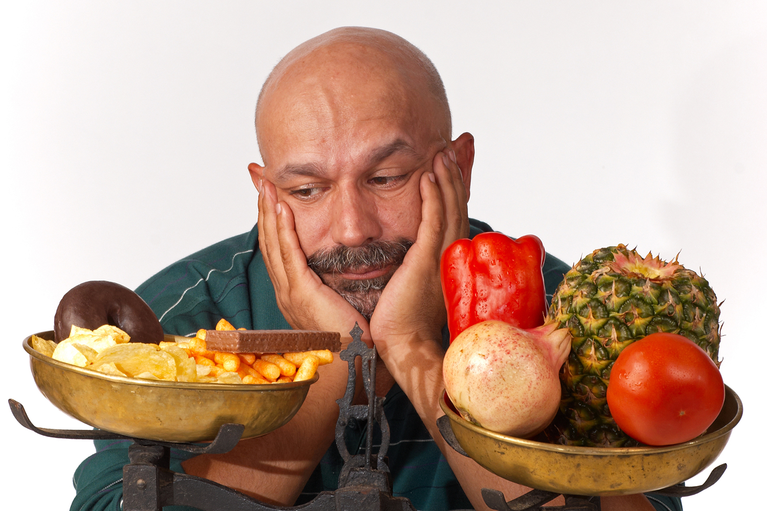 a disappointed man weighing fruits and veggies against fried food