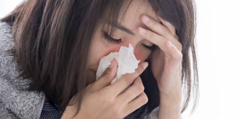 a stressed woman sneezing into a tissue
