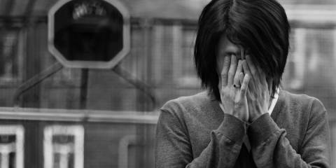 Black and white image of a woman holding her hands over her face.