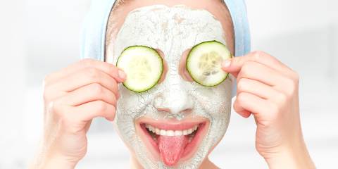 a woman with a facial mask and cucumbers over her eyes