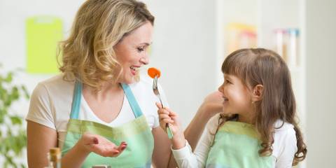 Child feeding mother vegetables.