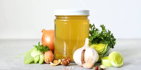 a jar of broth and some prepped vegetables