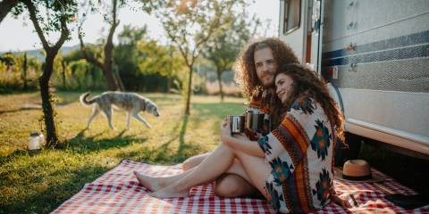 a couple drinking herbal tea while camping in a caravan
