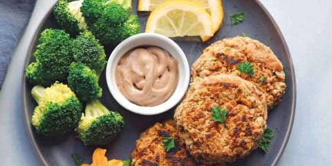 tuna cakes plated with hummus, broccoli, and lemon slices