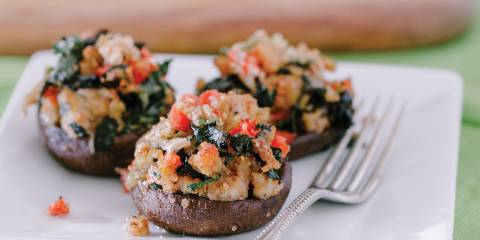 Stuffed crimini mushrooms on a white square plate with fork.