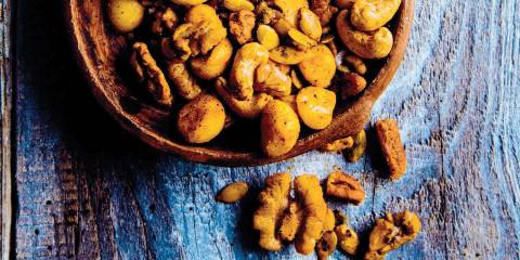 Taco-Spiced Mixed Nuts in a wooden bowl on a blue stained wooden table.