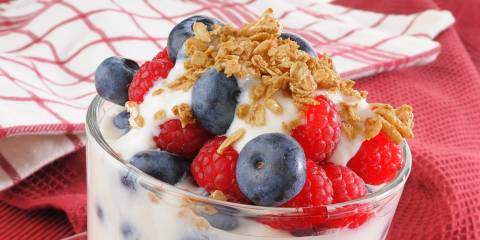 a yogurt parfait with granola, nuts, and berries in a glass