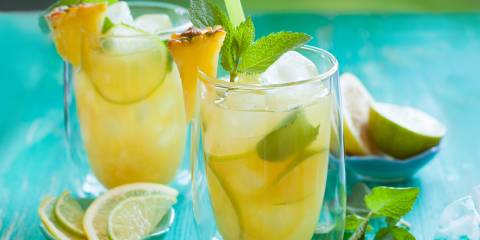 two glasses of pineapple citrus juice with a leafy green garnish