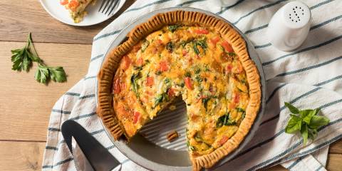 a pie tin of vegetable quiche missing a slice