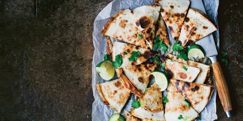 Top view of Portobello and Avocado Quesadillas on parchment paper cut into wedges to serve.