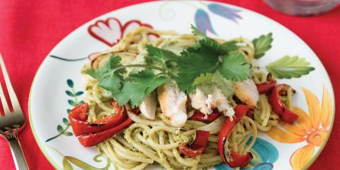 Roasted Poblano Creamy Spaghetti with Grilled Chicken, Onions, & Peppers on a colorful plate with a red tablecloth background.