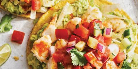 a tortilla slathered with guacamole and piled with shrimp and other toppings