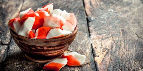 Crab meat in a bowl. On a wooden background.