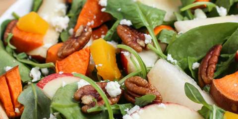 a salad with sweet potatoes, spinach, and nuts