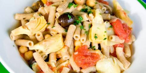 a plate of penne with olives and artichokes