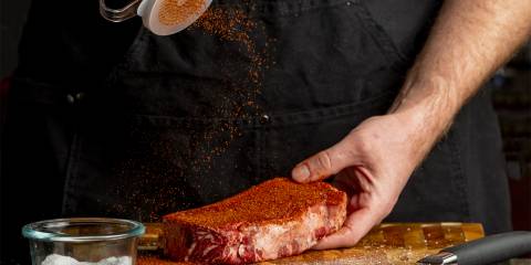 a man sprinkling dry rub on a strip steak