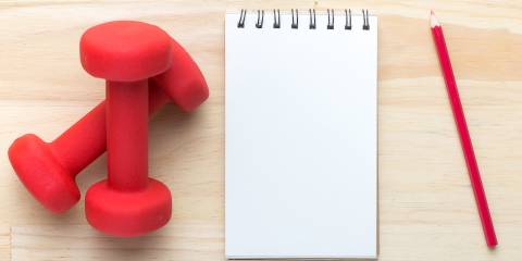 a pair of weights and a notepad ready for your plan