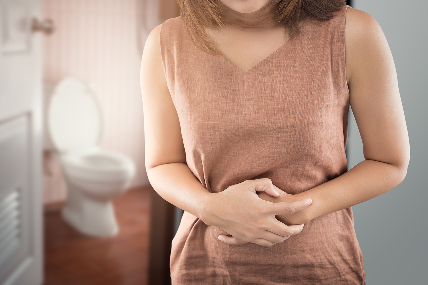 A woman outside the bathroom with bowel cramps from bloating